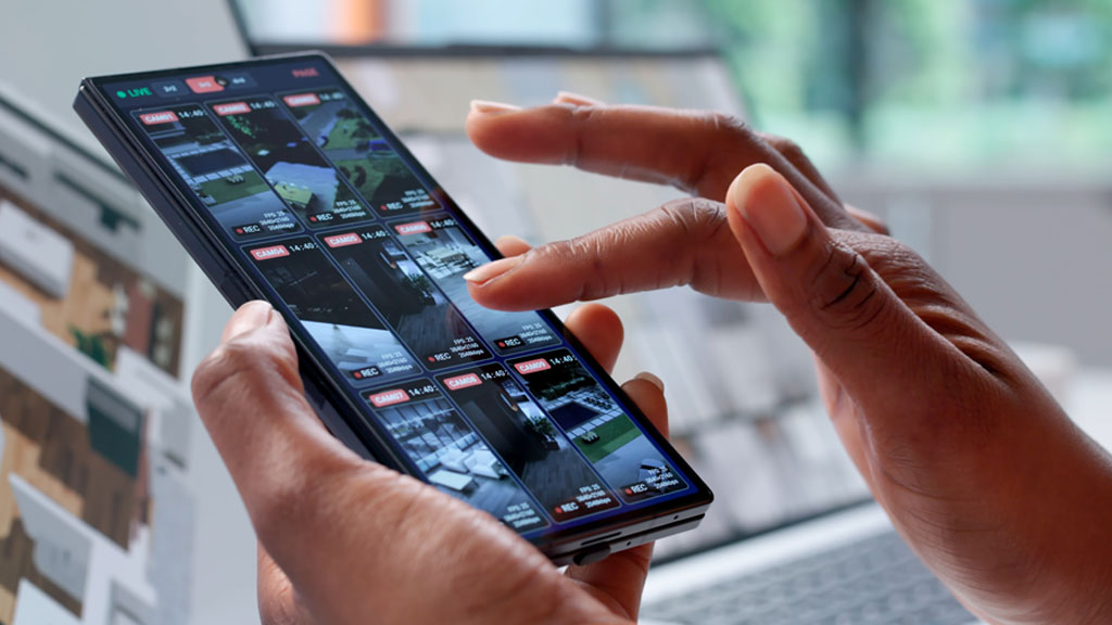 Femme consultant une application de sécurité sur smartphone dans son salon
